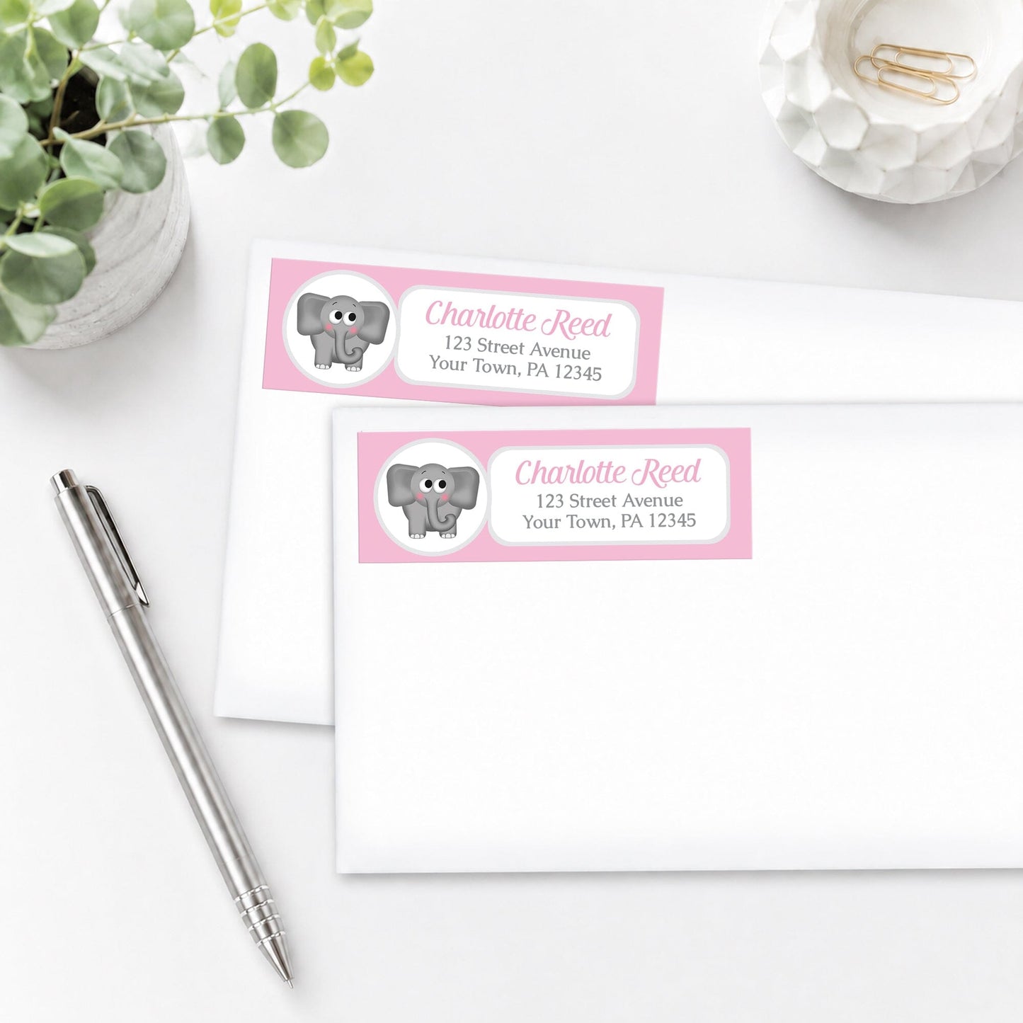 Cute Elephant Pink Address Labels, shown on white envelopes, on a white surface with a pen and plant.