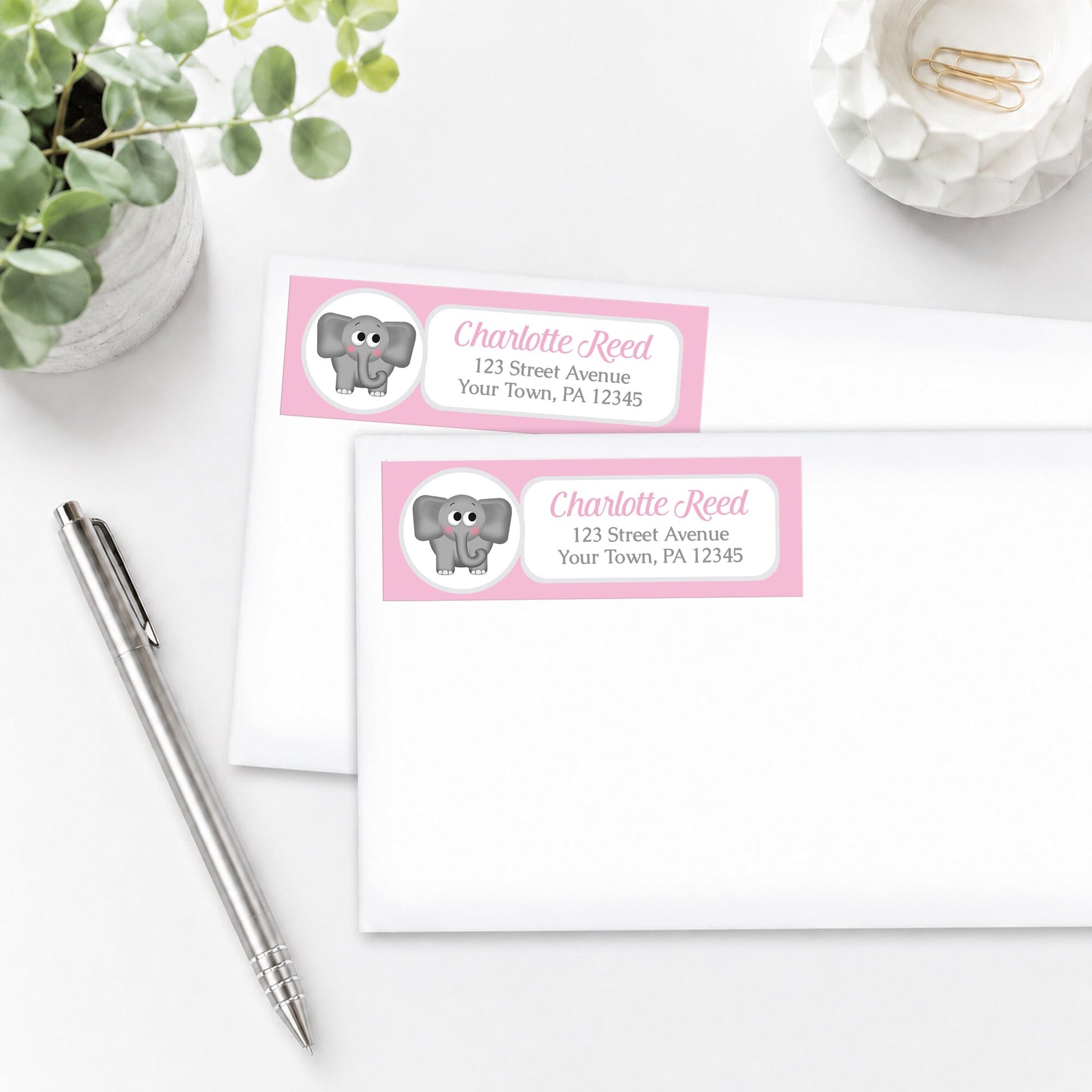 Cute Elephant Pink Address Labels, shown on white envelopes, on a white surface with a pen and plant.