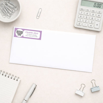 Cute Elephant Purple Address Label shown on a white envelope with everyday office supplies