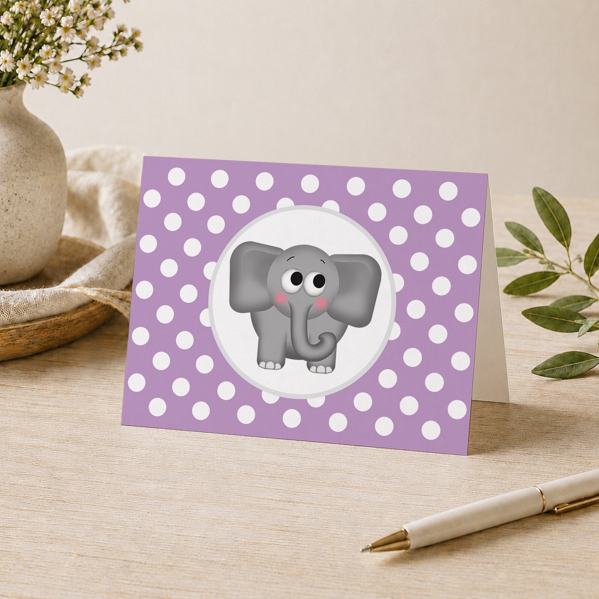 Cute Elephant Purple Polka Dot Note Card shown on a desk with a vase, plants, and a pen.