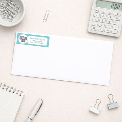 Cute Elephant Turquoise Address Label shown on a white envelope with everyday office supplies