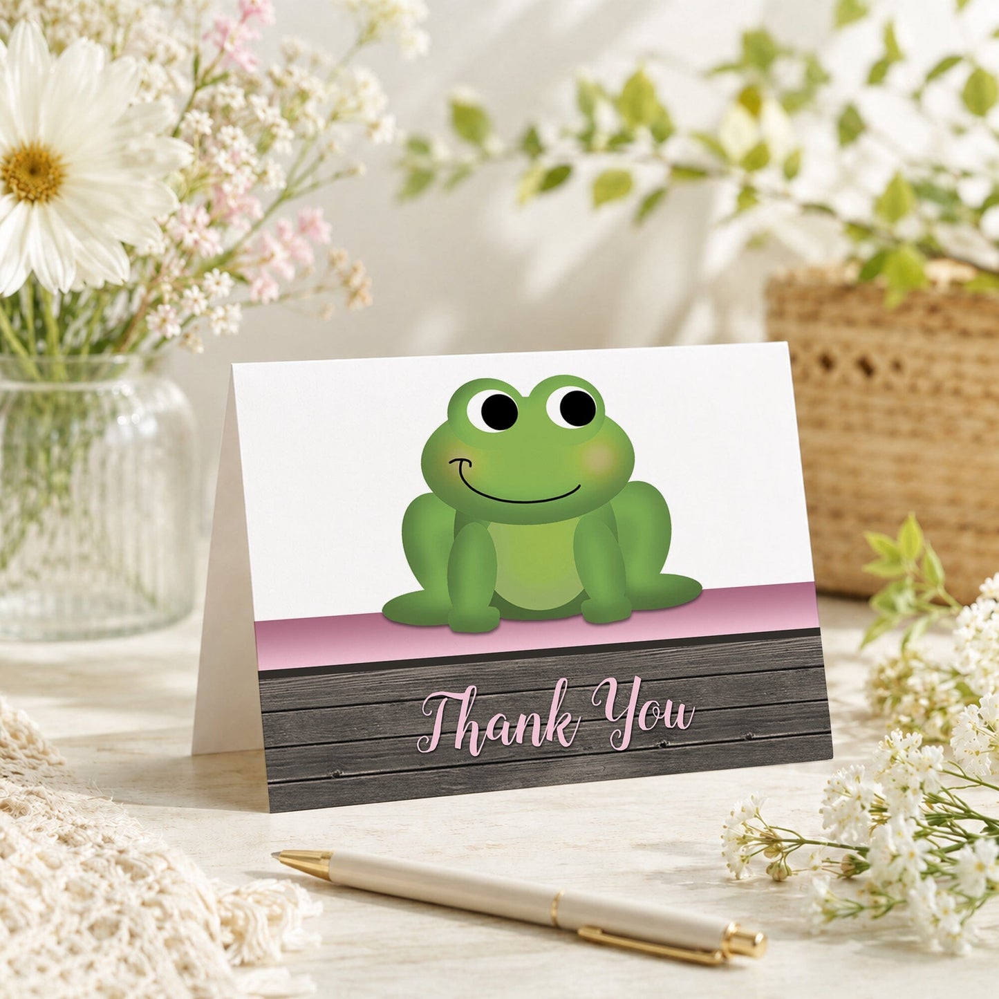 Cute Frog Green Pink Rustic Wood Thank You Card shown on a tabletop with a vase, spring and summer flowers, and a pen.