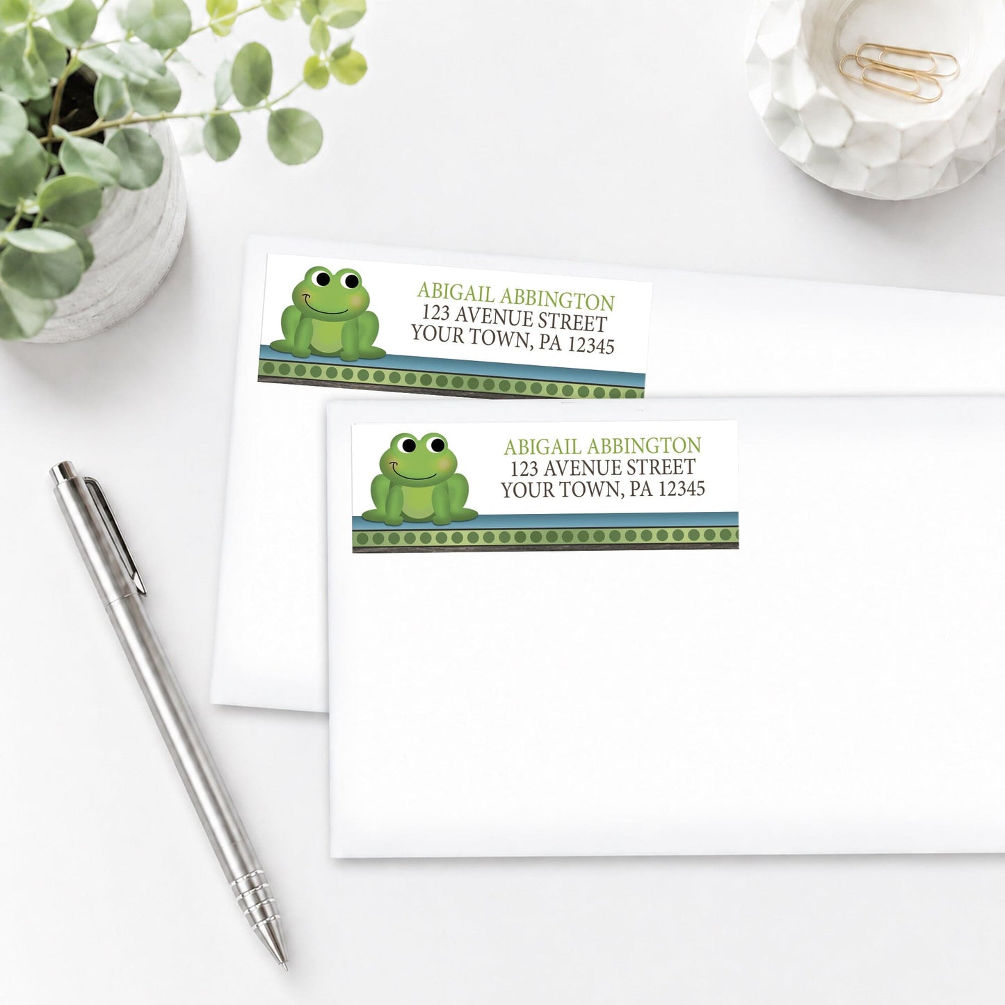 Cute Frog Green Rustic Brown Address Labels, shown on white envelopes, on a white surface with a plant and a pen.