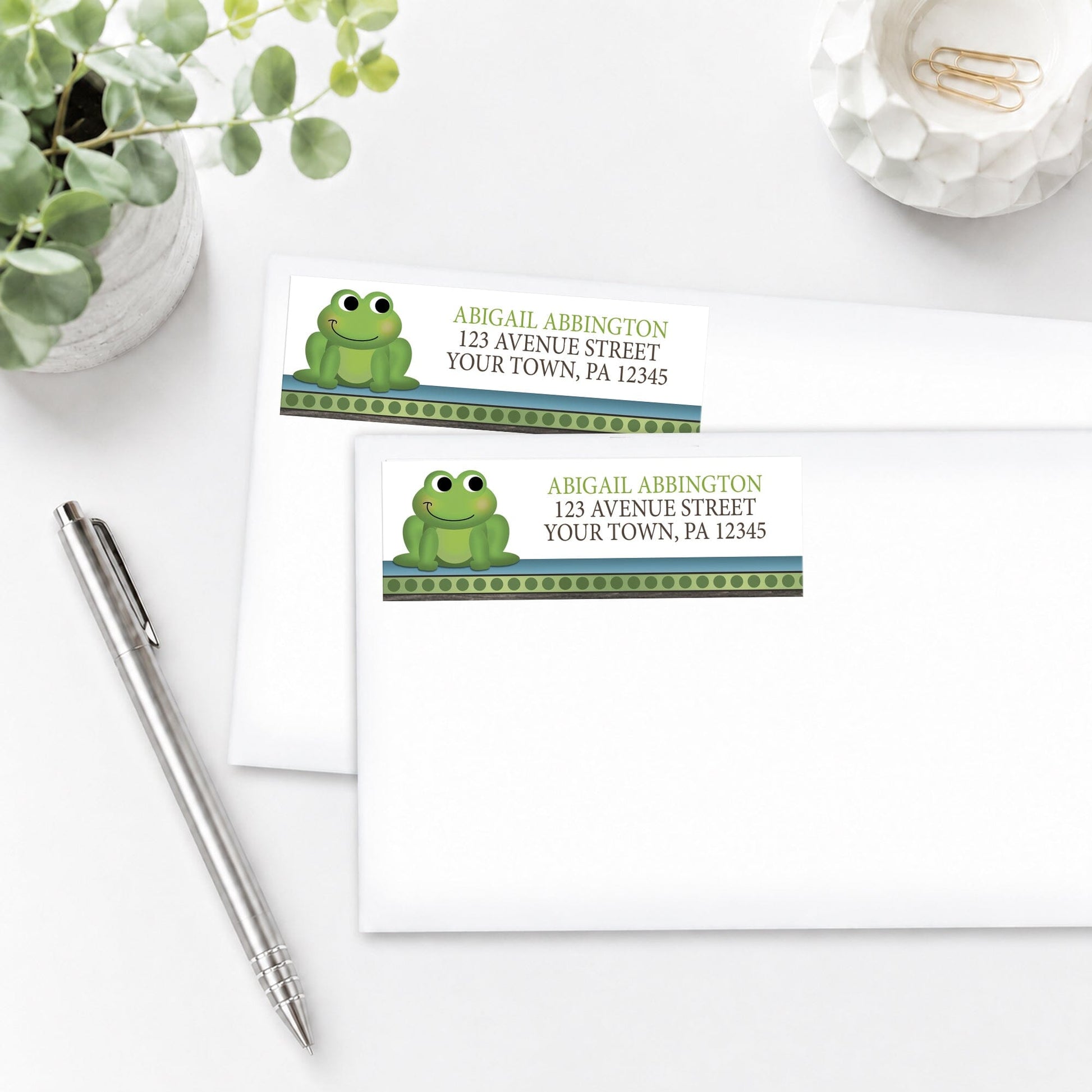 Cute Frog Green Rustic Brown Address Labels, shown on white envelopes, on a white surface with a plant and a pen.