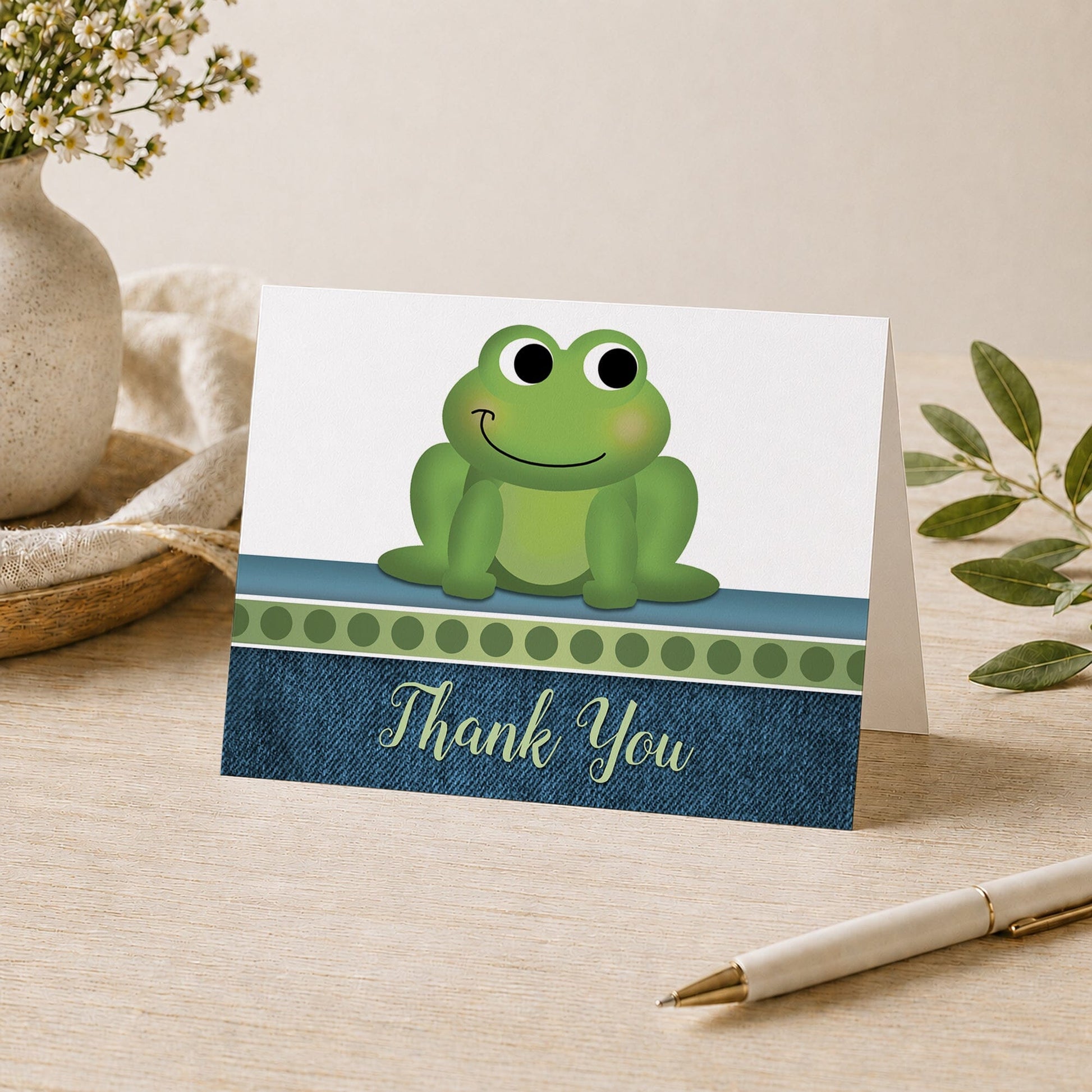 Cute Frog Green Rustic Denim Thank You Card shown on a desk with a vase, plants, and a pen.