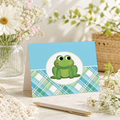Cute Frog Green and Blue Plaid Note Card shown on a tabletop with a vase, spring and summer flowers, and a pen.