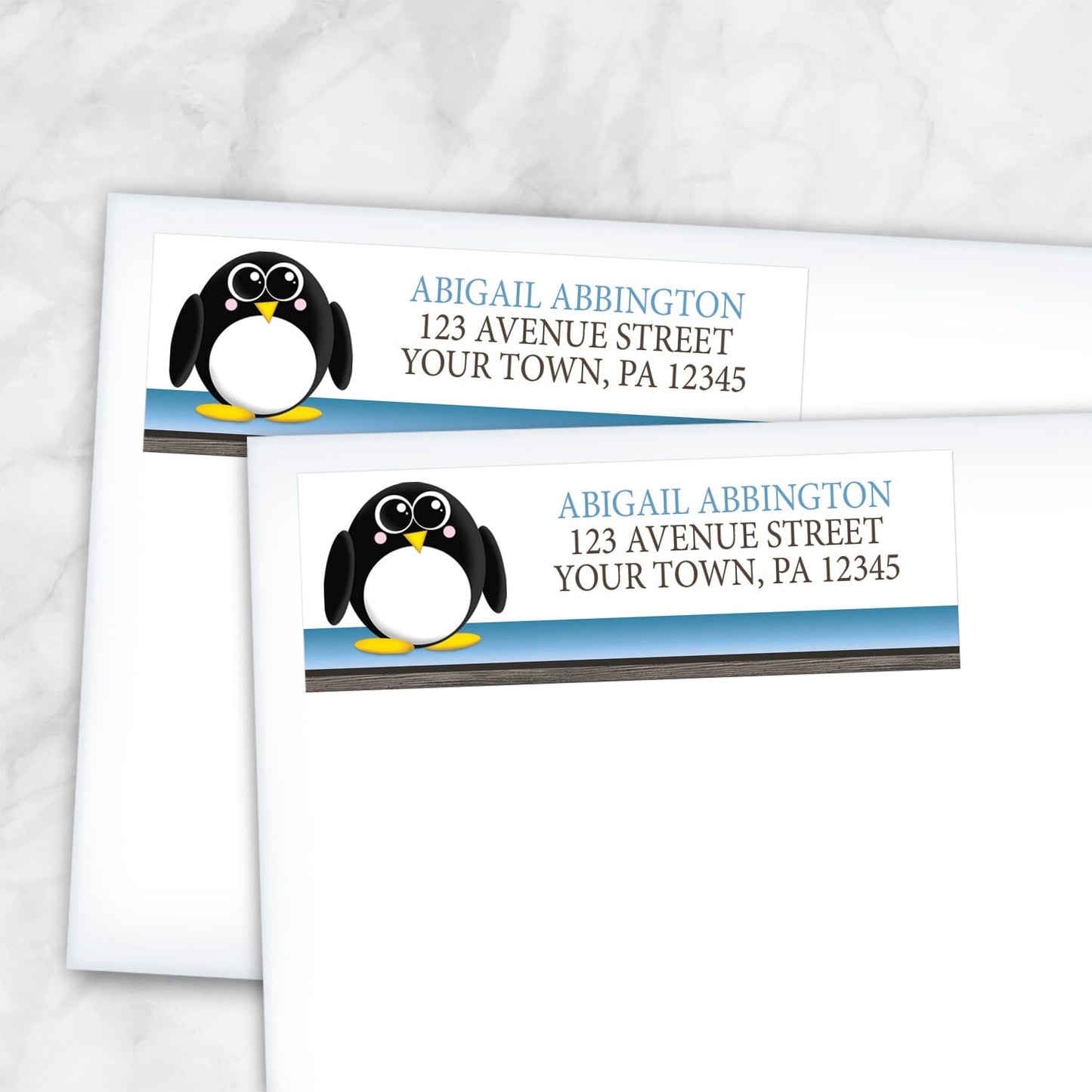 2 Cute Penguin Blue Rustic Address Labels shown on white envelopes on a marble surface