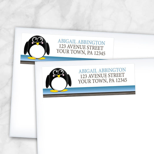 2 Cute Penguin Blue Rustic Address Labels shown on white envelopes on a marble surface