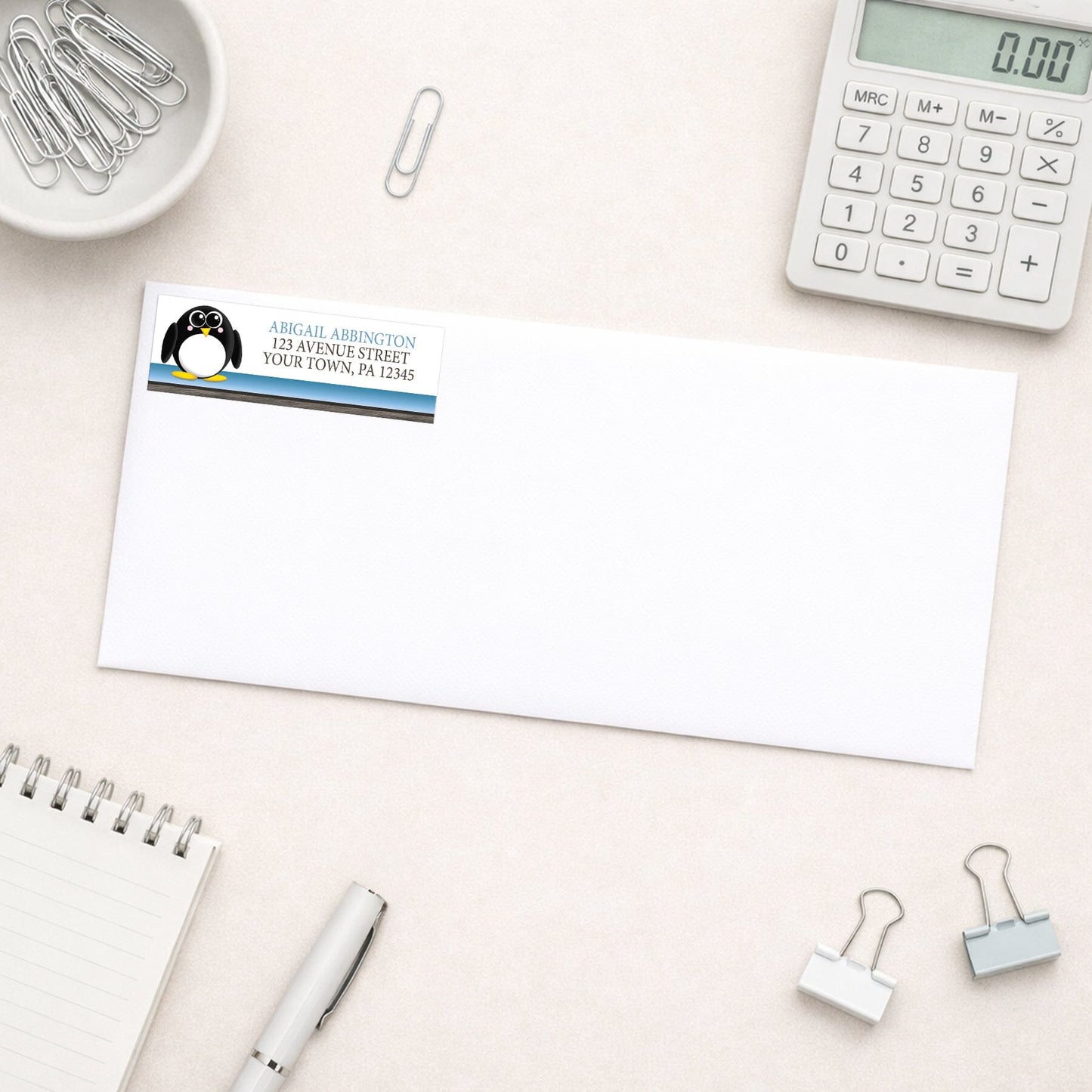 Cute Penguin Blue Rustic Address Label shown on a white envelope with everyday office supplies