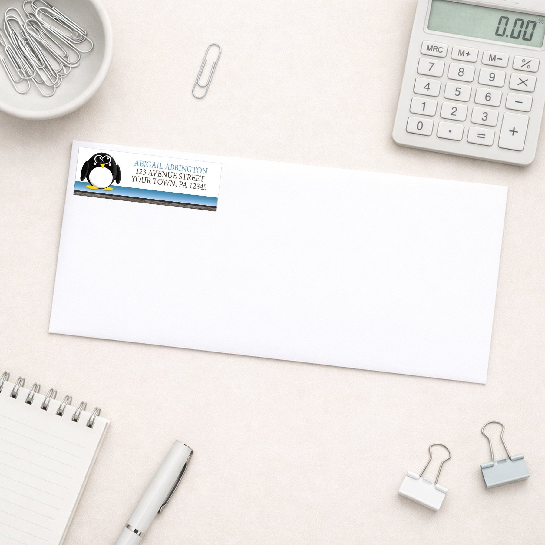 Cute Penguin Blue Rustic Address Label shown on a white envelope with everyday office supplies