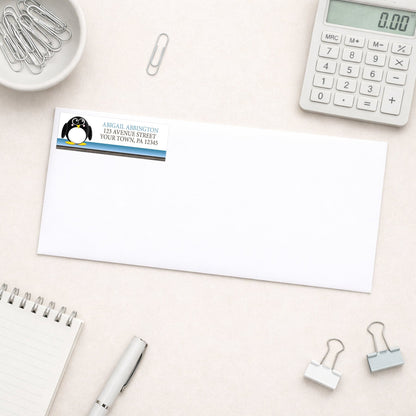 Cute Penguin Blue Rustic Address Label shown on a white envelope with everyday office supplies