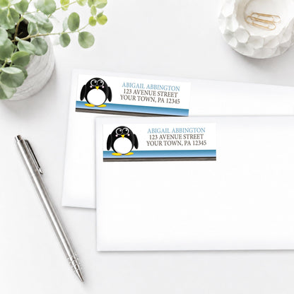 Cute Penguin Blue Rustic Address Labels on white envelopes, shown on a white surface with a plant and a pen.