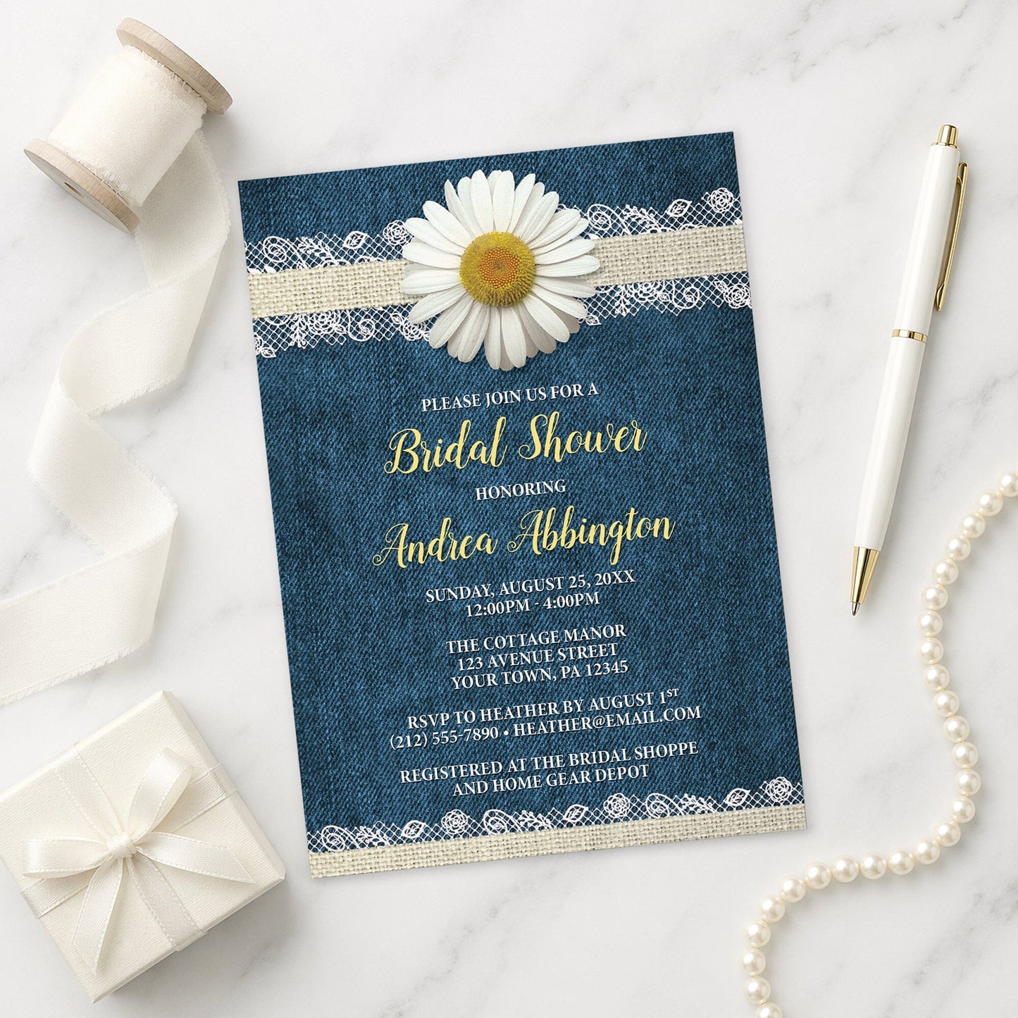 Daisy Burlap and Lace Denim Bridal Shower Invitation on a marble surface with a white gift box, pen, ribbon, and pearls.