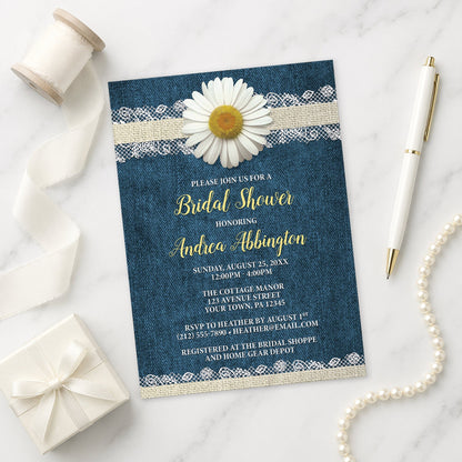 Daisy Burlap and Lace Denim Bridal Shower Invitation on a marble surface with a white gift box, pen, ribbon, and pearls.