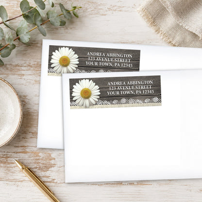 Daisy Burlap and Lace Wood Address Labels shown on white envelopes on a wooden surface with a plant and a pen.