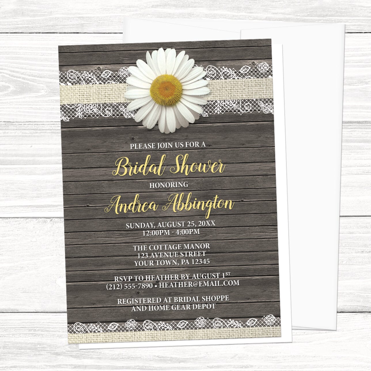 Floral bridal shower invitations with an illustrated design featuring a white dairy, burlap and lace, and a rustic wood background, displayed with a white envelope on a white wood surface