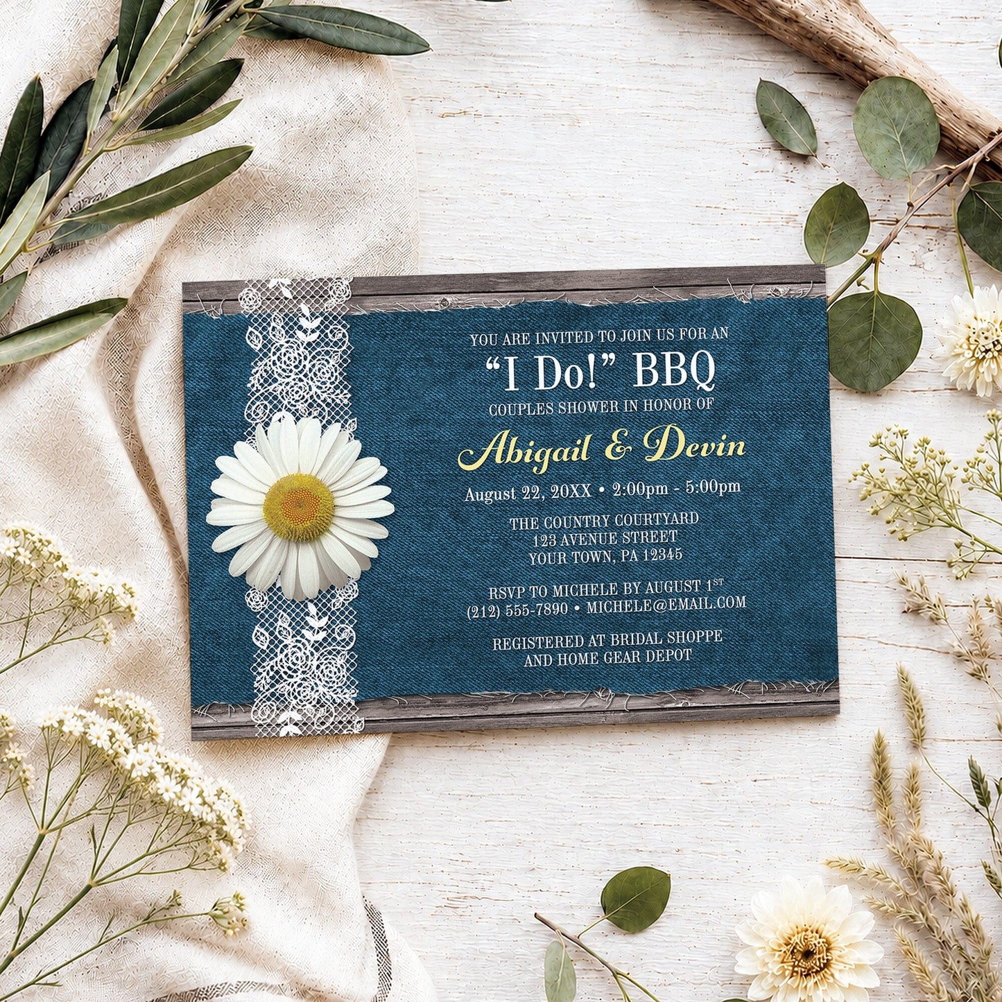 Daisy Denim and Lace I Do BBQ Couples Shower Invitation shown on a light wooden surface with spring and summer plants.