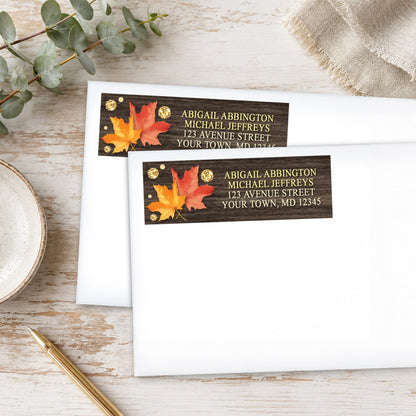Falling Leaves with Gold Autumn Address Labels, shown on white envelopes, on a wooden surface with eucalyptus leaves and a pen.