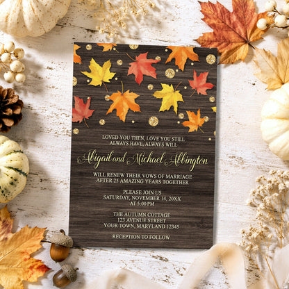Falling Leaves with Gold Autumn Vow Renewal Invitation on a light wooden surface with fall leaves, pumpkins, and autumn decor.