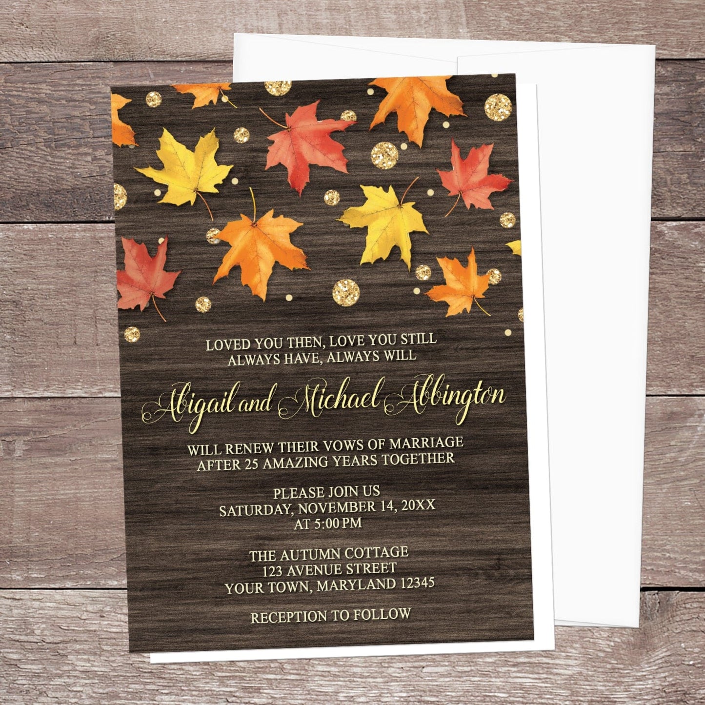 Falling Leaves with Gold Autumn Vow Renewal Invitation on a brown wooden surface with a white envelope.