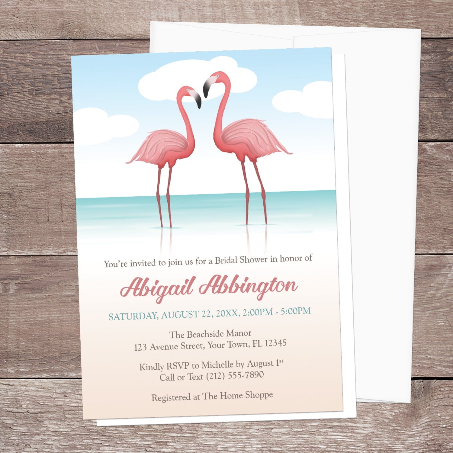Flamingo-themed bridal shower invitation displayed with a white envelope on a wooden surface