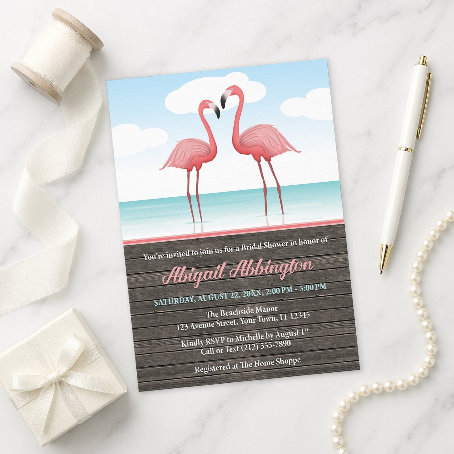 Flamingos in the Water Rustic Bridal Shower Invitation on a marble surface with decorative items.