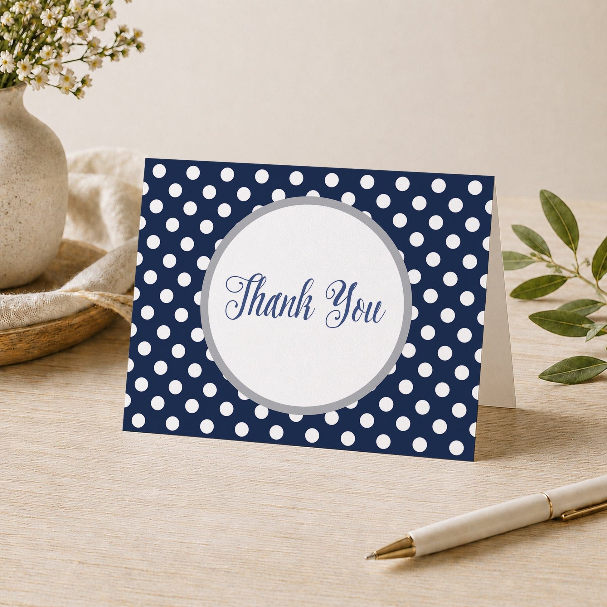 Gray Navy Blue Polka Dot Thank You Card shown on a desk with a vase, plants, and a pen.