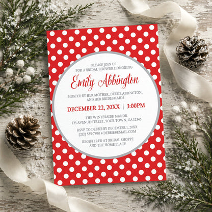 Gray and Red Polka Dot Bridal Shower Invitation shown on a rustic wooden surface with winter greenery, pine cones, and ribbons.