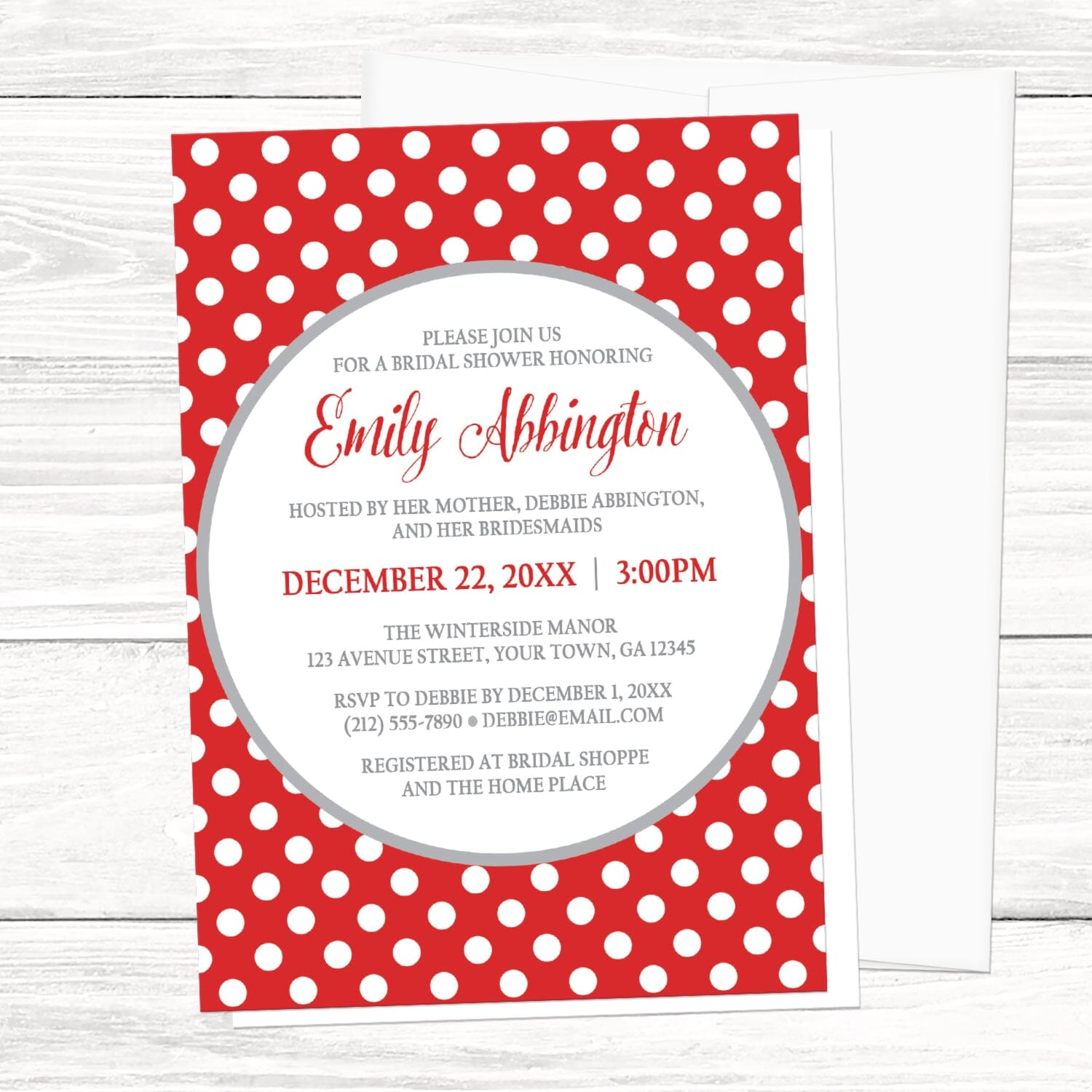 Gray and Red Polka Dot Bridal Shower Invitation on a light wood surface with a white envelope.
