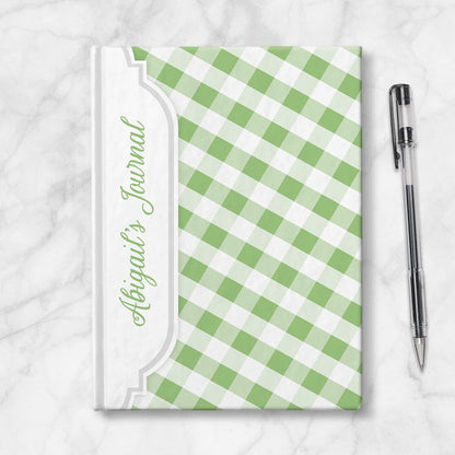 Personalized Green Gingham Journal at Artistically Invited. Image shows the book on a countertop next to a pen.