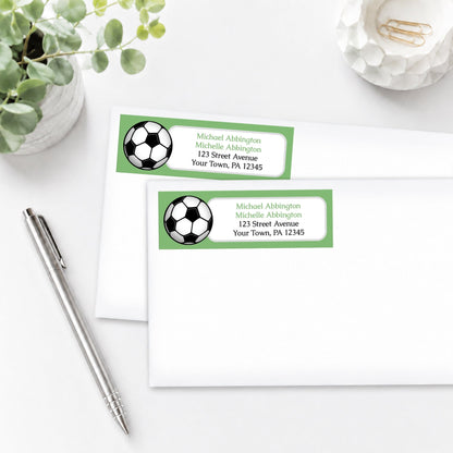 Green Soccer Ball Address Labels on white envelopes, shown on a white surface with a plant and a pen.