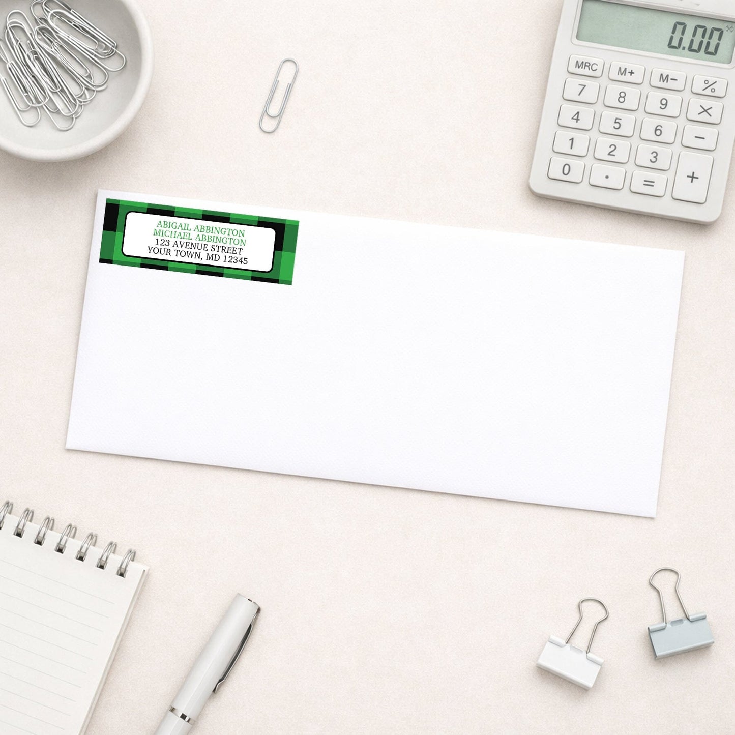 Green and Black Buffalo Plaid Address Label shown on a white envelope with everyday office supplies