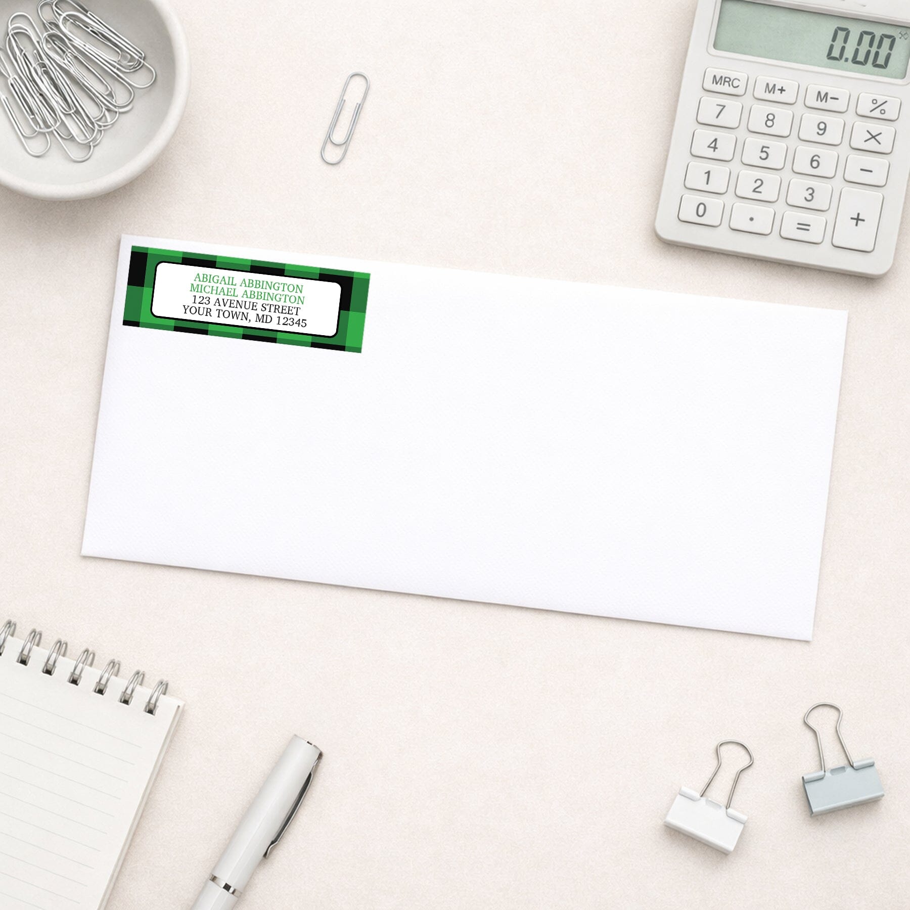 Green and Black Buffalo Plaid Address Label shown on a white envelope with everyday office supplies