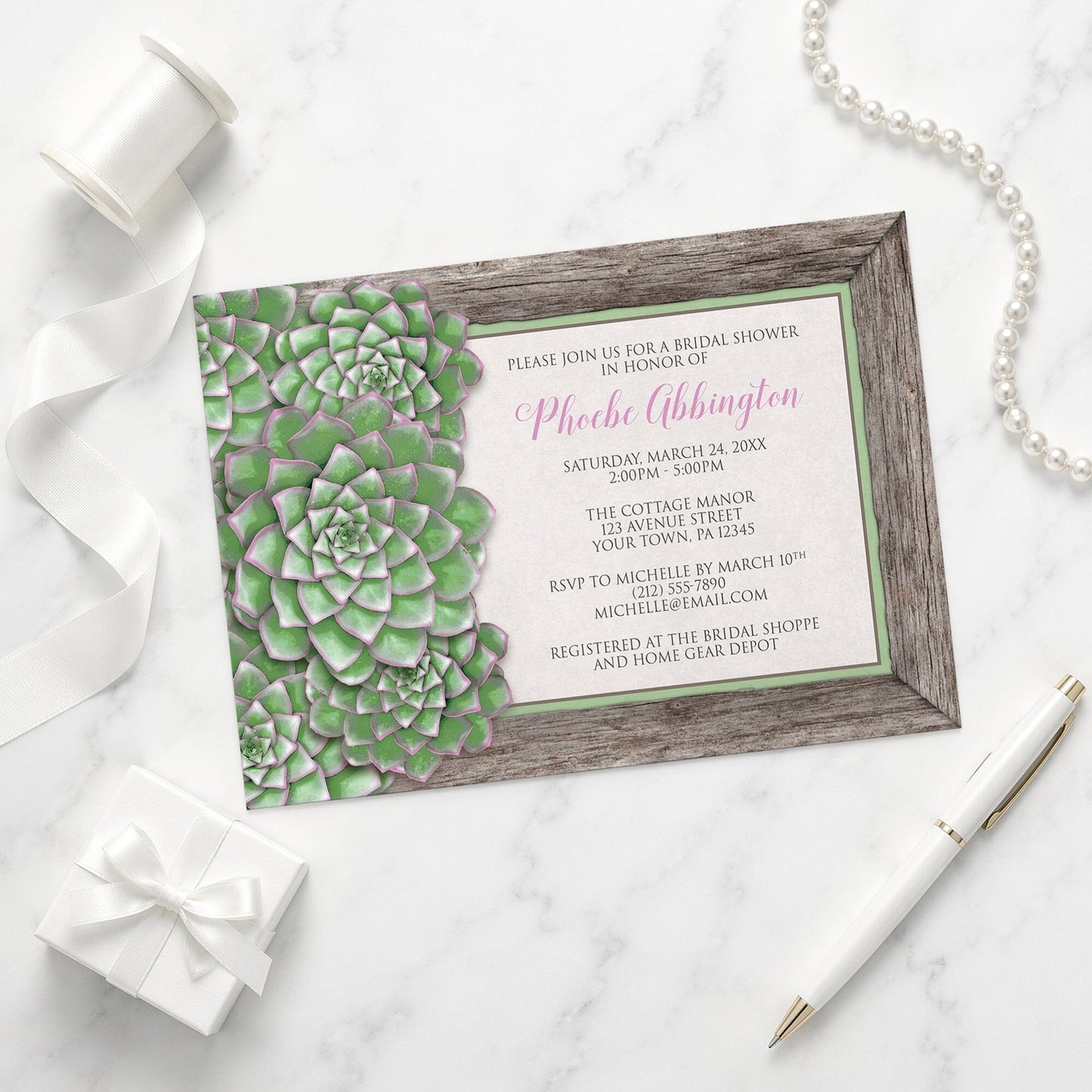 Green and Pink Succulent Wood Bridal Shower Invitation on a marble surface with a white gift box, ribbon, pen, and pearls.
