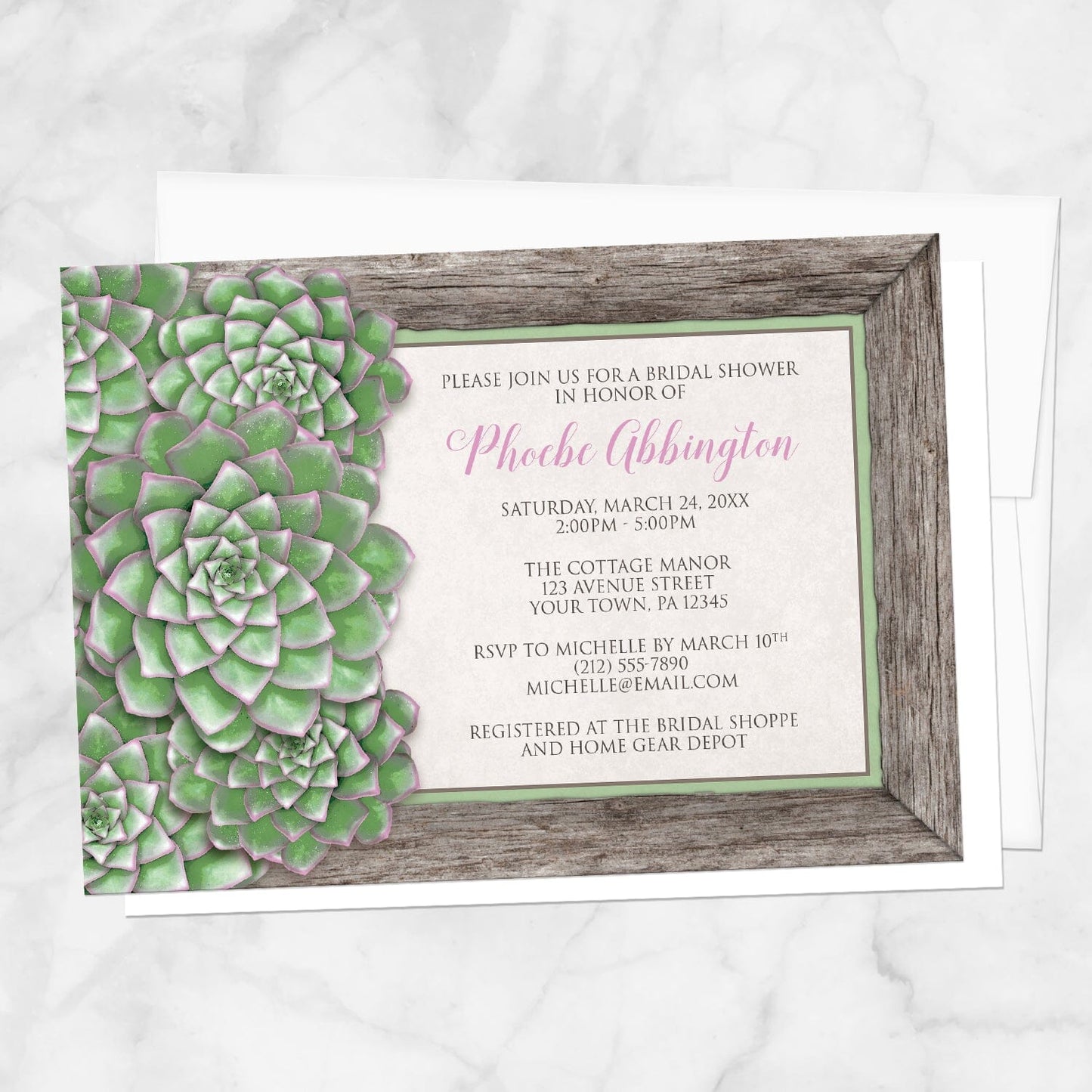 Bridal shower invitation with green succulent design and pink accents, displayed with a white envelope on a marble surface