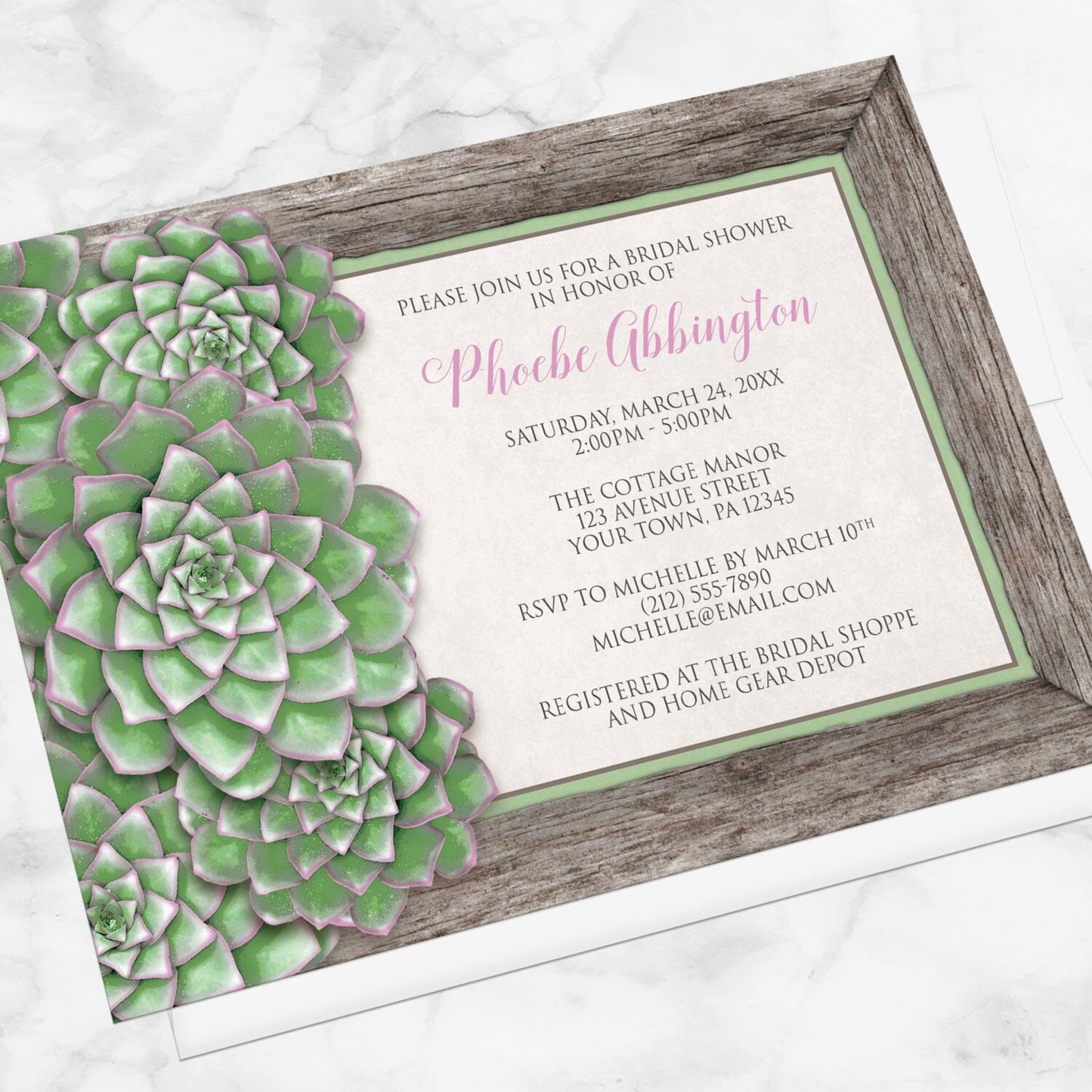 Bridal shower invitation with green succulent design and pink accents, displayed at an angle with a white envelope on a marble surface