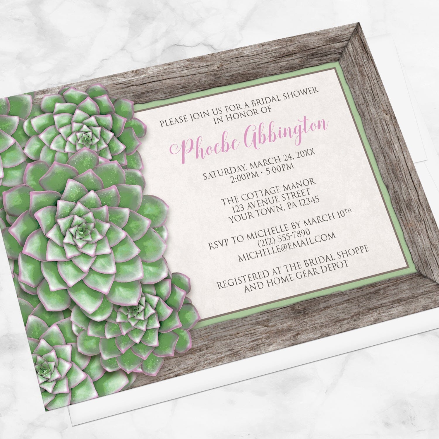 Bridal shower invitation with green succulent design and pink accents, displayed at an angle with a white envelope on a marble surface