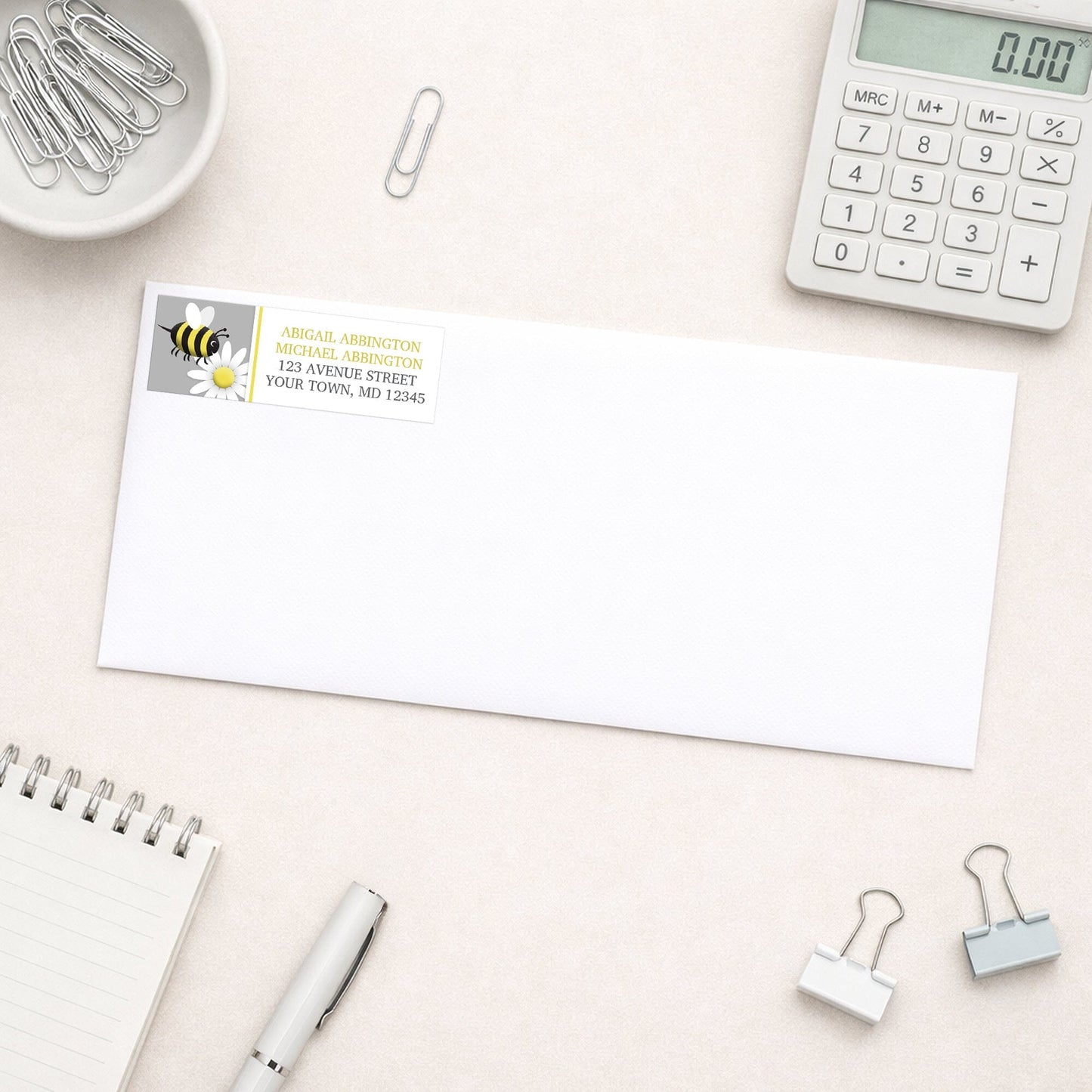 White envelope with a Happy Bee and Daisy Address Label on a desk with office supplies