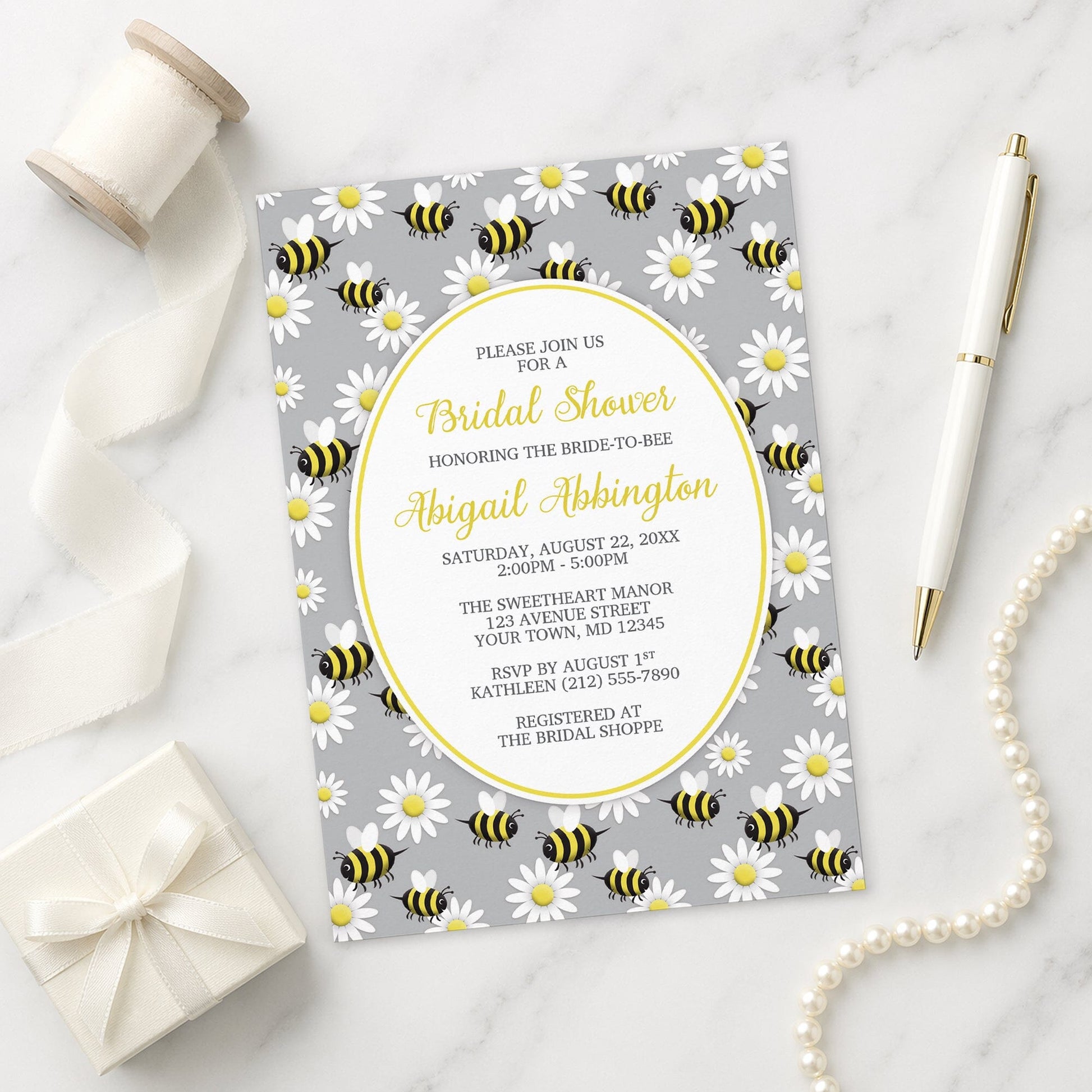 Happy Bee and Daisy Pattern Bridal Shower Invitation on a marble surface with a gift box, pen, and pearls.