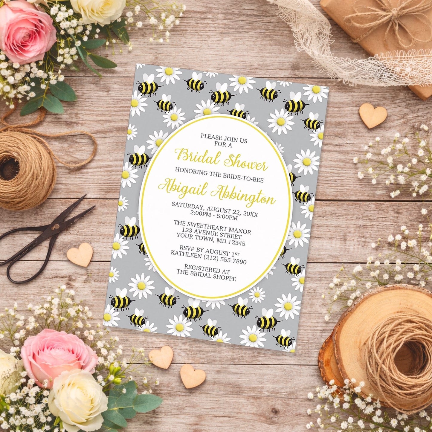Happy Bee and Daisy Pattern Bridal Shower Invitation on a rustic wood surface with spring and summer flowers and twine.