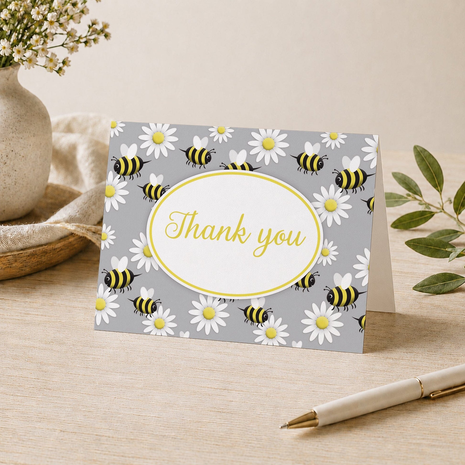 Happy Bee and Daisy Pattern Thank You Card shown on a desk with a vase, plants, and a pen.