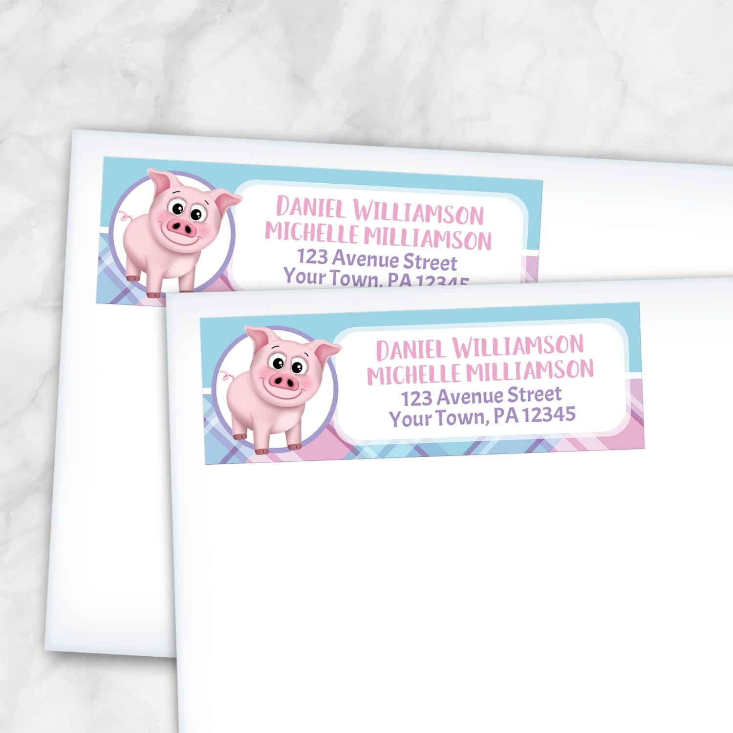2 Happy Pig Pink Blue and Purple Plaid Address Labels shown on white envelopes on a marble surface