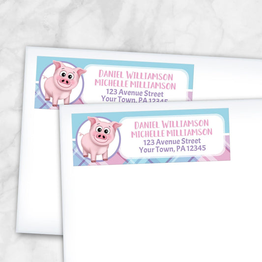2 Happy Pig Pink Blue and Purple Plaid Address Labels shown on white envelopes on a marble surface