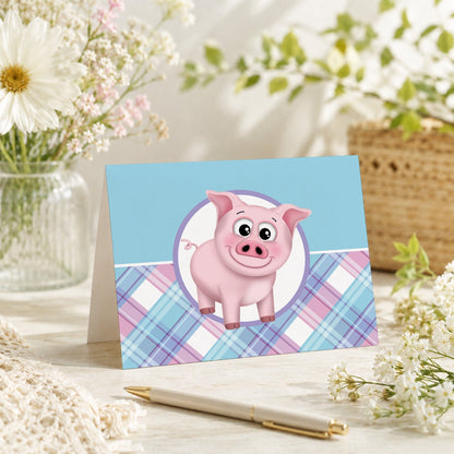 Happy Pig Pink Blue and Purple Plaid Note Card shown on a tabletop with a vase, spring and summer flowers, and a pen.