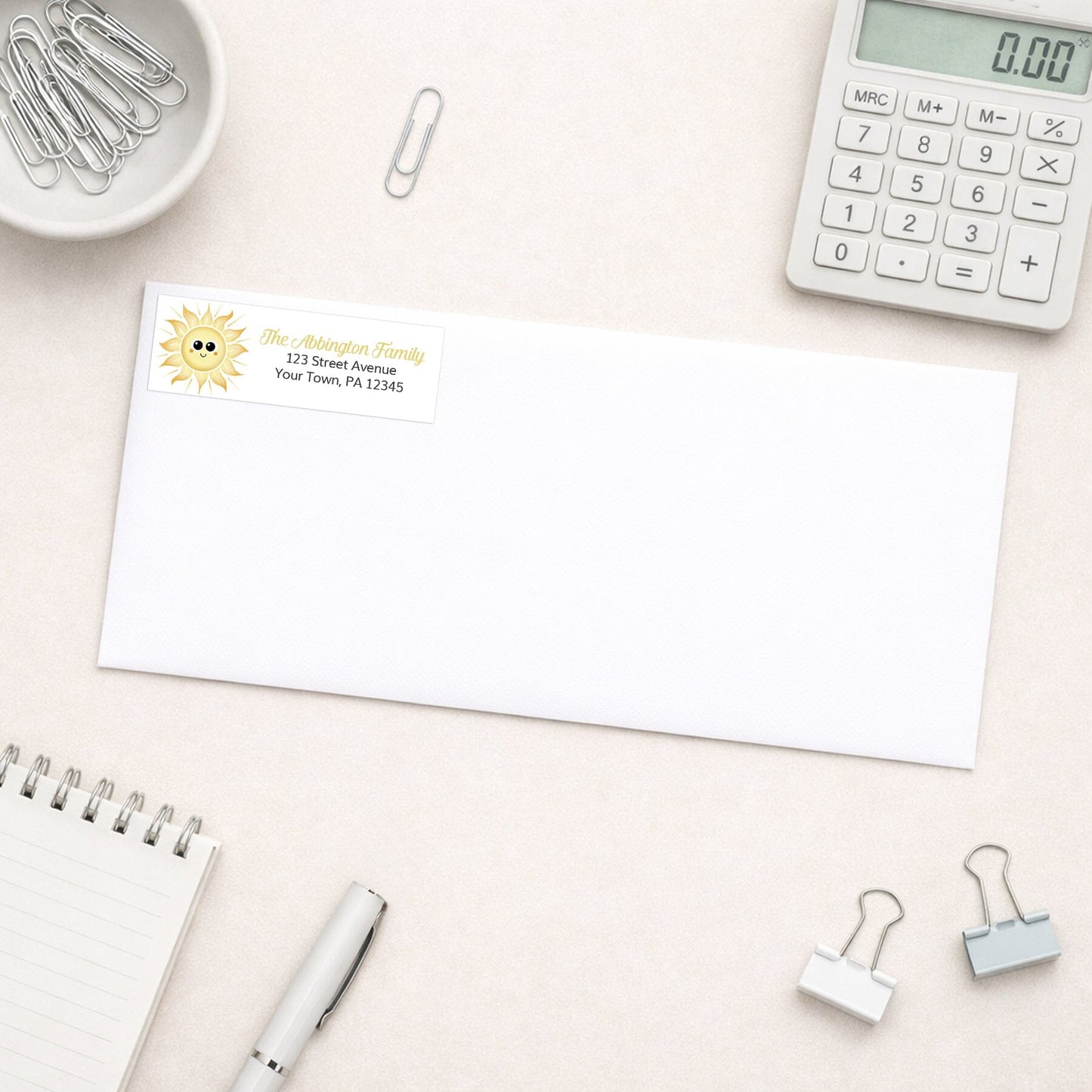 White envelope shown with the personalized Happy Sun Address Label on a desk with office supplies