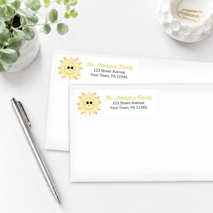 Happy Sun Address Labels on white envelopes shown on a white surface with a plant and a pen.