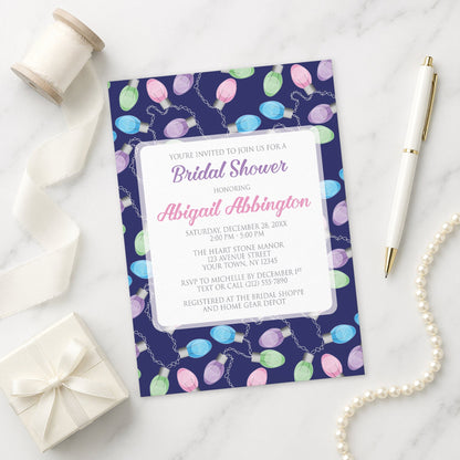 Holiday Lights Pattern Bridal Shower Invitation shown on a marble surface with a white gift box, pen, ribbon, and pearls.