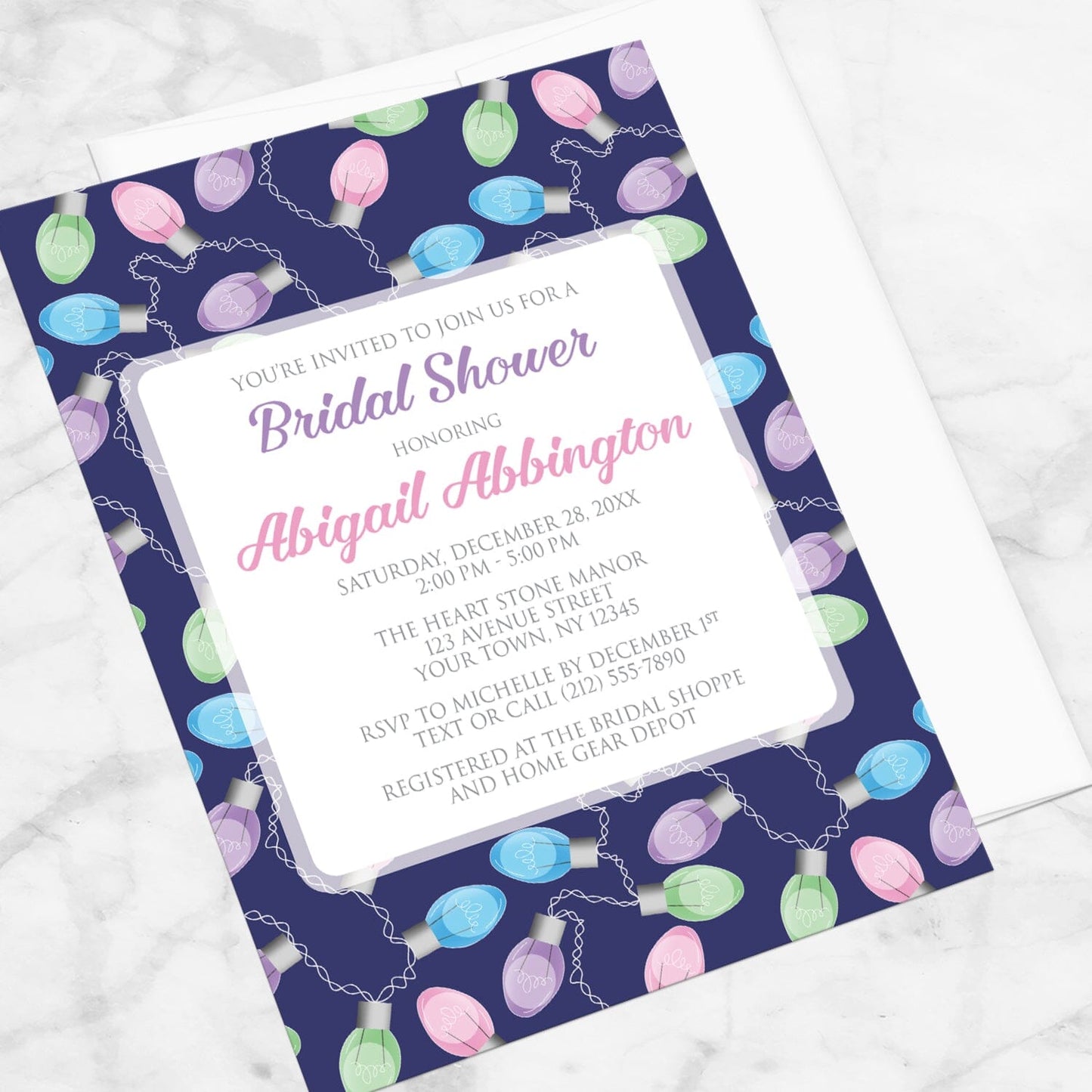Holiday Lights Pattern Bridal Shower Invitation shown at an angle on a marble surface with a white envelope.