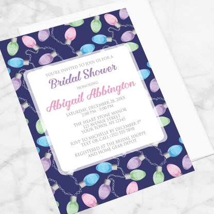 Holiday Lights Pattern Bridal Shower Invitation shown at an angle on a marble surface with a white envelope.