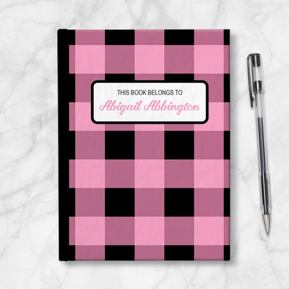 Personalized Light Pink and Black Buffalo Plaid Journal at Artistically Invited. Image shows the book on a countertop next to a pen.